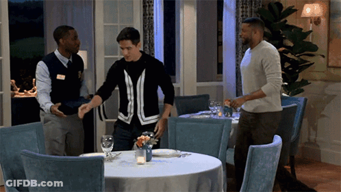 Man In Black And White Sweater Standing In Restaurant GIF