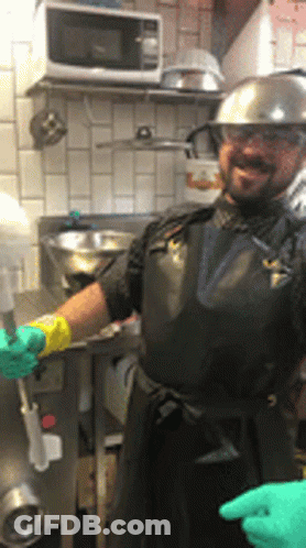 Man In Black Apron And Hard Hat In Kitchen GIF