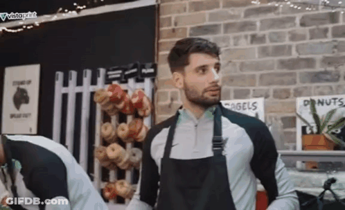 Man In Black Apron Standing In Front Of Brick Wall GIF