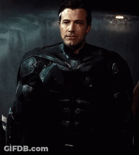 Man In Black Armored Suit Standing In Dark Room GIF