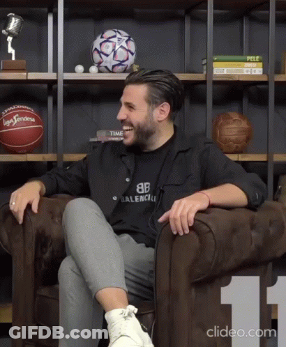 Man In Black Balenciaga Shirt Sitting On Couch GIF