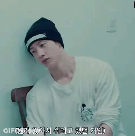 Man In Black Beanie And White Shirt With Chinese Writing Sitting In Chair GIF