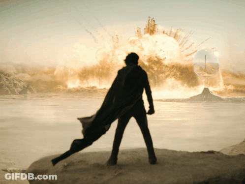 Man In Black Cape On Rock Before Explosion GIF