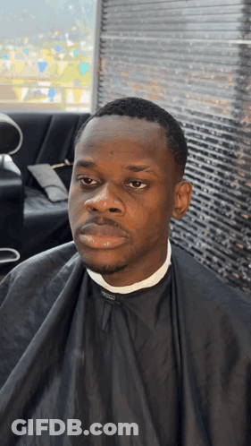 Man In Black Cape Sitting In Barber Chair GIF
