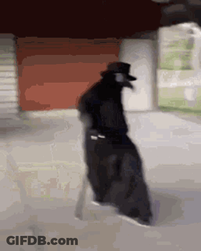 Man In Black Cloak And Top Hat Walking Down Street GIF