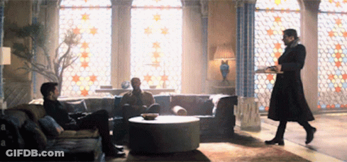 Man In Black Coat Holding Tray In Living Room GIF