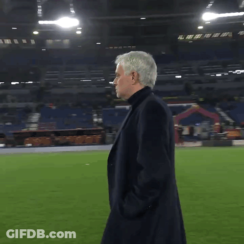Man In Black Coat On Soccer Field With Hands In Pockets GIF