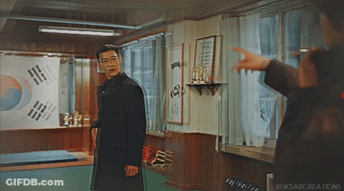 Man In Black Coat Pointing At Flag On Wall GIF