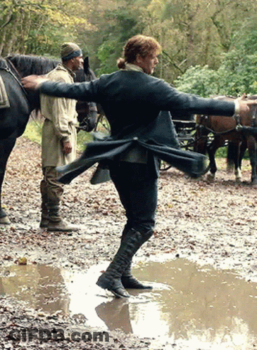 Man In Black Coat Standing In Muddy Puddle GIF