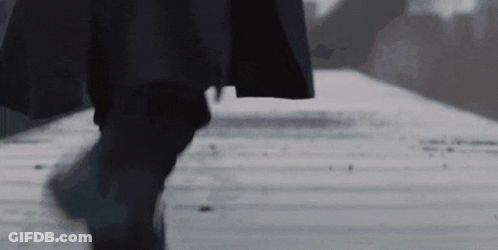 Man In Black Coat Walking Down Sidewalk Black And White Photo GIF