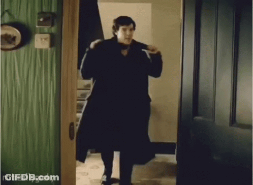Man In Black Coat Walking Out Of Doorway GIF