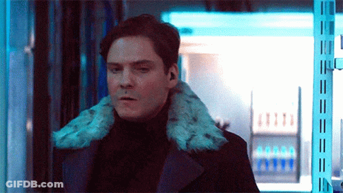 Man In Black Coat With Fur Collar Standing In Room GIF