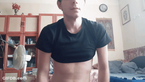 Man In Black Crop Top Standing In Room With Clock GIF