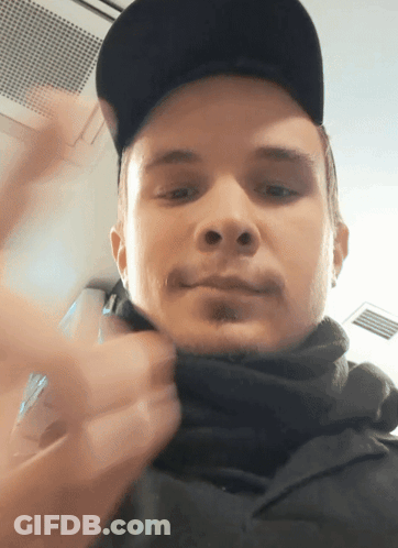 Man In Black Hat And Scarf Looking At Camera GIF