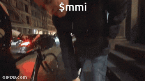 Man In Black Hat Standing In Front Of $MMI Sign GIF