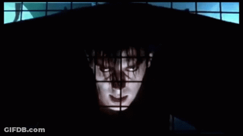 Man In Black Hood Standing In Front Of Window GIF