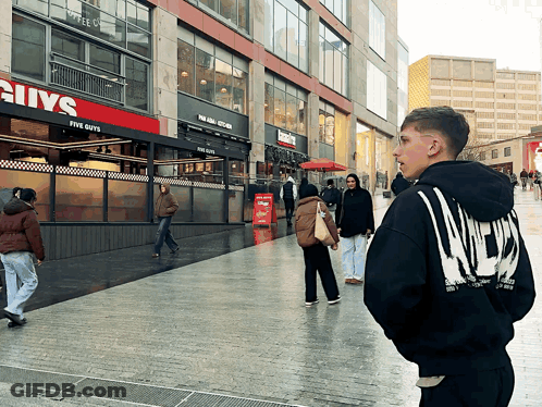 Man In Black Hoodie In Front Of Five Guys GIF