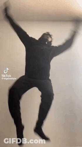 Man In Black Hoodie Jumping With Arms Outstretched GIF