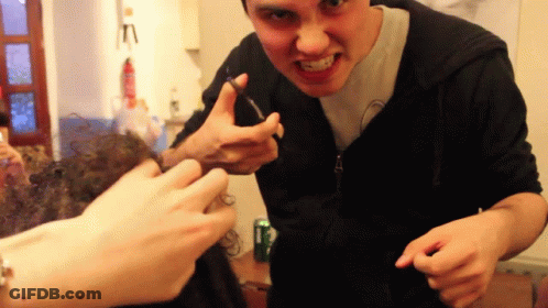 Man In Black Hoodie Making Funny Face With Scissors GIF