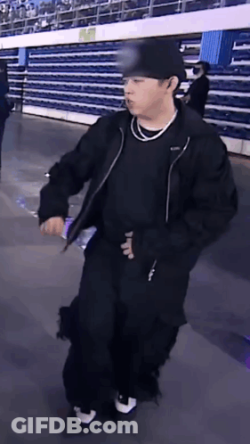 Man In Black Jacket And Hat Holding Water Bottle In Stadium GIF