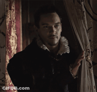 Man In Black Jacket And White Collar Standing By Window GIF