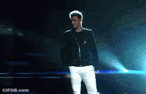 Man In Black Jacket And White Pants On Stage Holding Microphone GIF