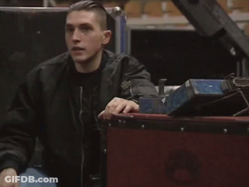 Man In Black Jacket Beside Wooden Box Saying A GIF