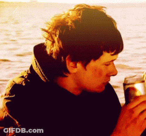 Man In Black Jacket Drinking From Can In Front Of Ocean GIF