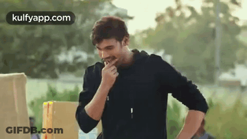 Man In Black Jacket Eating In Front Of Box GIF