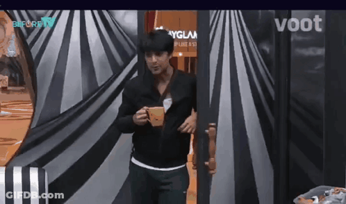 Man In Black Jacket Holding Coffee In Front Of Voot Sign GIF