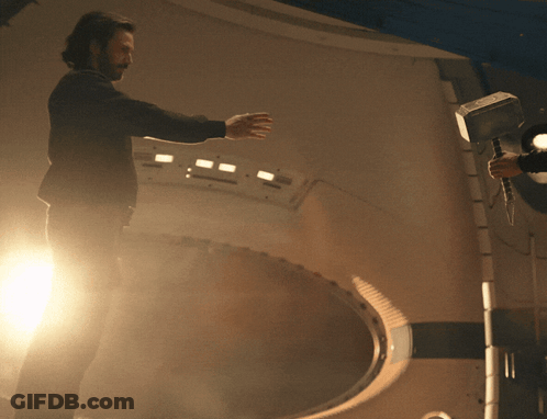 Man In Black Jacket Holding Hammer In Dark Room GIF