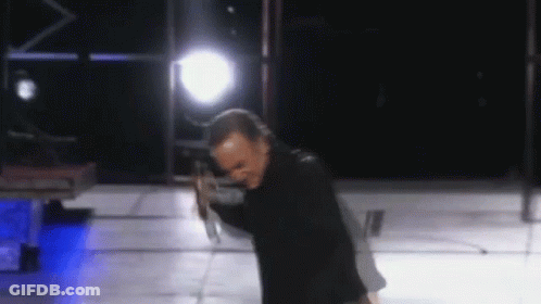 Man In Black Jacket Holding Microphone On Stage GIF