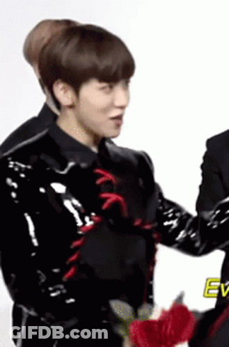 Man In Black Jacket Holding Red Flower Next To Another Man GIF