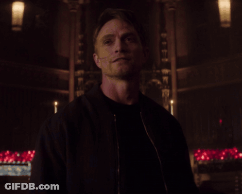 Man In Black Jacket In Dark Room With Candles GIF