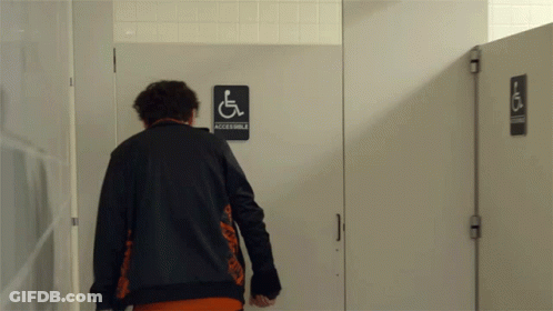 Man In Black Jacket In Front Of Accessible Sign GIF