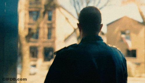 Man In Black Jacket In Front Of Blurry Building GIF
