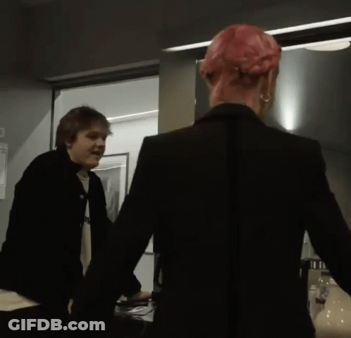 Man In Black Jacket Next To Woman With Pink Hair GIF