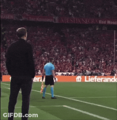 Man In Black Jacket On Soccer Field With Lieferand Banner GIF