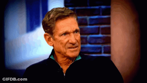 Man In Black Jacket Sitting By Brick Wall GIF