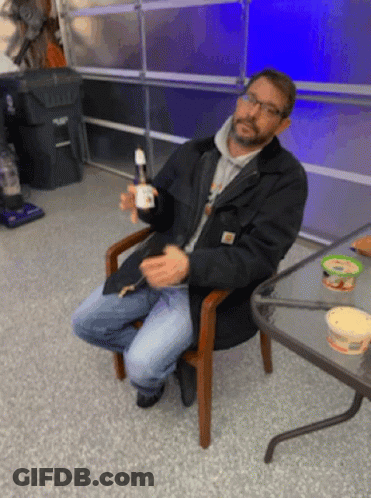 Man In Black Jacket Sitting Holding Bottle GIF