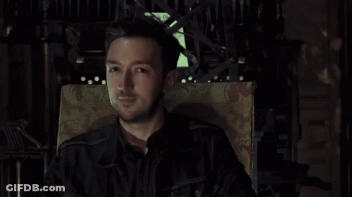 Man In Black Jacket Sitting In Chair Looking At Camera GIF
