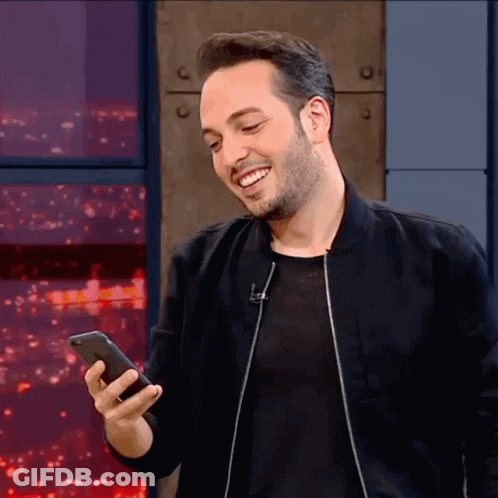 Man In Black Jacket Smiling Holding Phone GIF