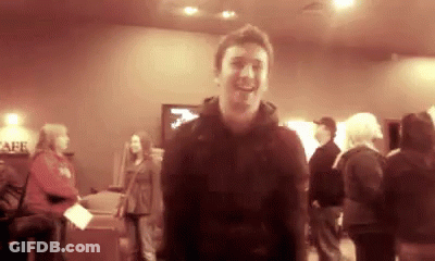 Man In Black Jacket Smiling In Crowded Room GIF