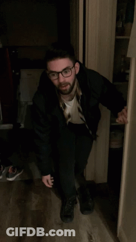 Man In Black Jacket Standing In Doorway With Arms Up GIF