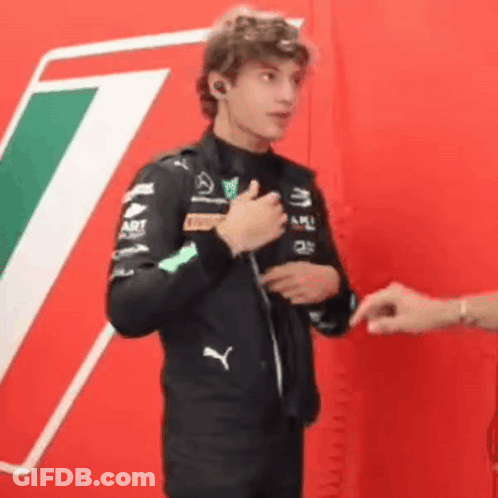 Man In Black Jacket Talking By Red Wall GIF