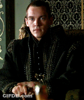 Man In Black Jacket With Gold Beads Sitting In Chair GIF