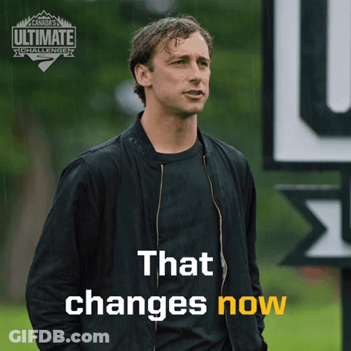 Man In Black Jacket With Sign That Changes Now GIF