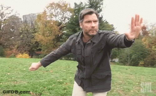 Man In Black Jacket With SNL Logo In Grassy Field GIF