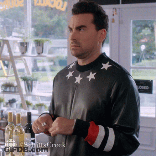 Man In Black Jacket With White Stars Standing In Front Of Closed Sign GIF