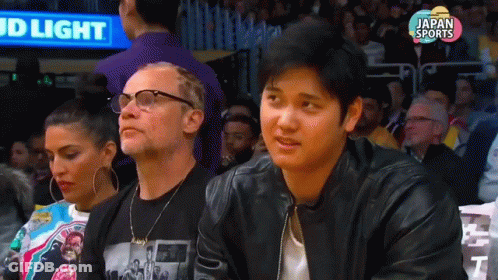 Man In Black Leather Jacket At Basketball Game With Bud Light Sign GIF